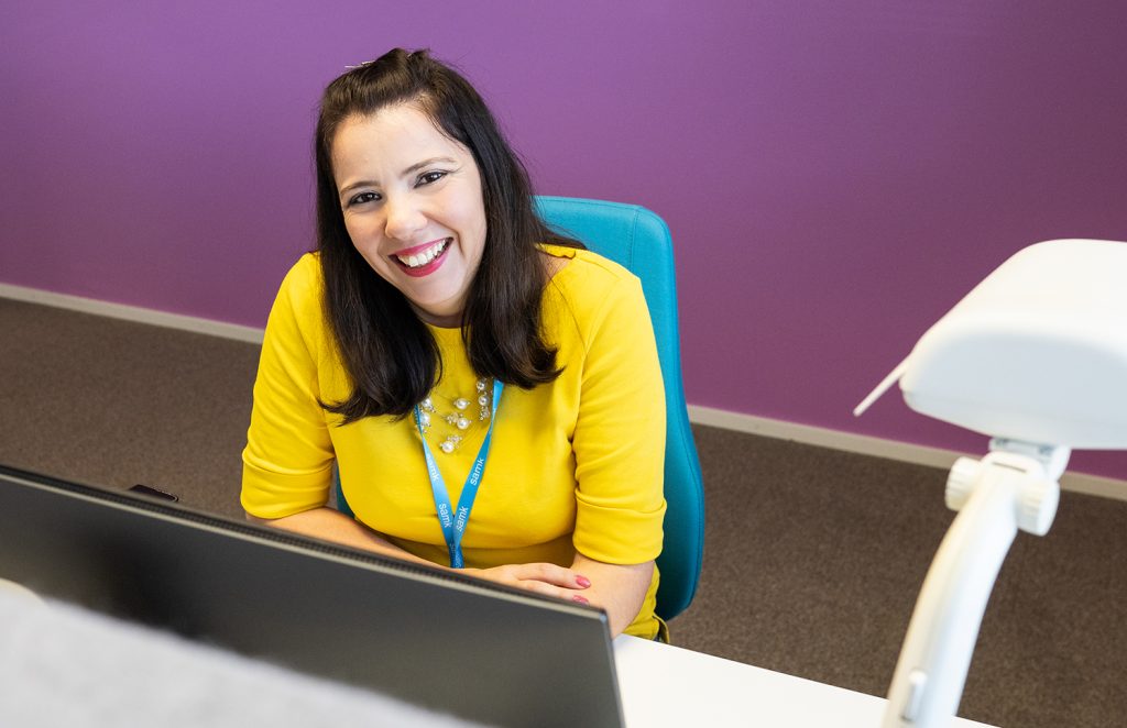 Woman sitting behind a desk and smiling.