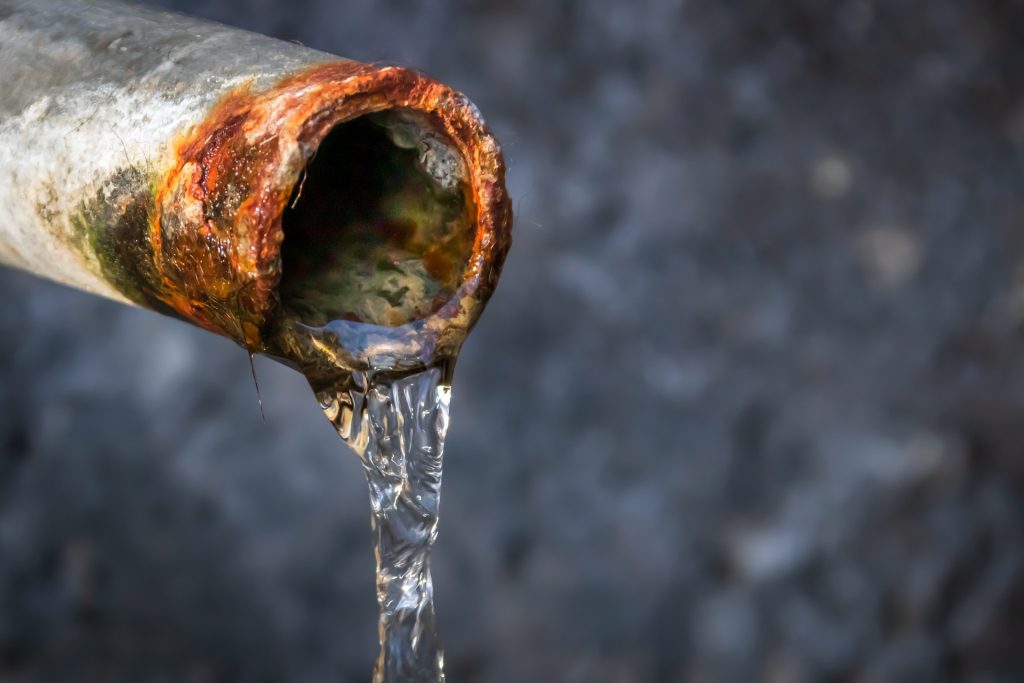 The picture shows water leaking from a dilapidated water pipe.