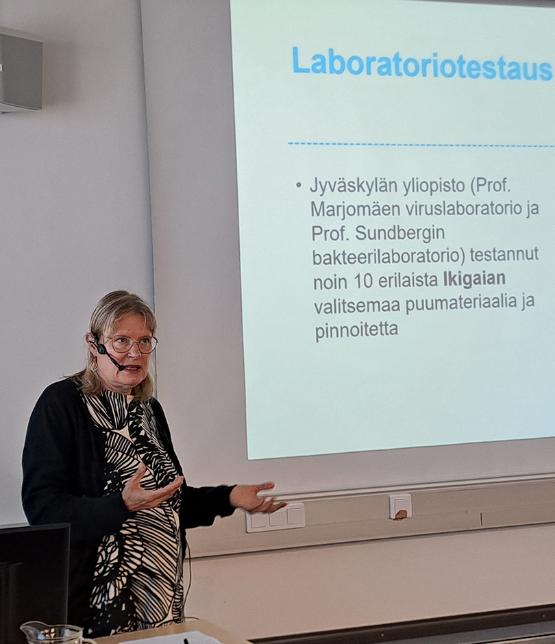 Henkilö pitää esitystä luentosalissa diasarjan äärellä.