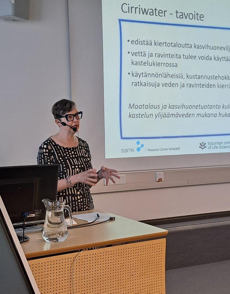 Henkilö pitää esitystä luentosalissa diasarjan äärellä.
